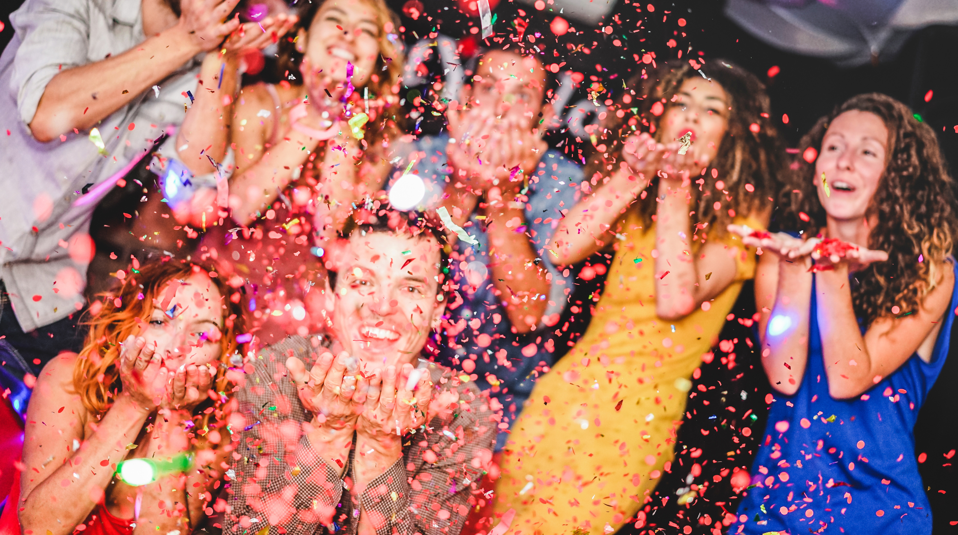 Students at a lively fiesta night event with colorful paper flags, red and yellow decorations, dancing and laughing